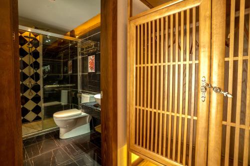 a bathroom with a toilet and a glass door at 张家界惹莲心栖墅·精品民宿 in Zhangjiajie
