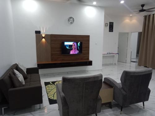 een woonkamer met een bank en een tv aan de muur bij Homestay Asam Pedas Parit Jawa Muar in Bakar Parit