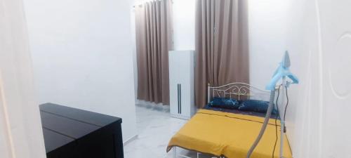 a bedroom with a yellow bed and a tv at Homestay Asam Pedas Parit Jawa Muar in Bakar Parit