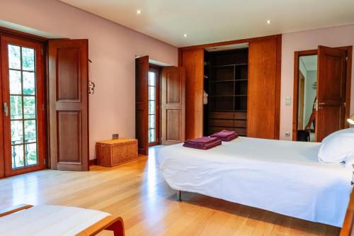 a bedroom with a large white bed and wooden floors at Casa das Gandas in Celeiró do Monte