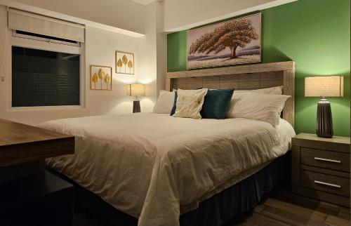 a bedroom with a large bed with a green wall at Torre Pamplona 402 -Nuevo y Cómodo- Apartamento in Guatemala