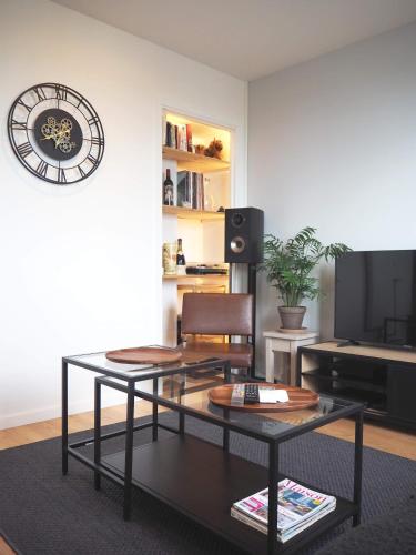 - un salon avec une table et une horloge murale dans l'établissement T2 style industriel avec balcon, à Toulouse