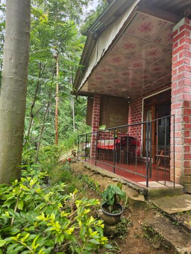 a porch of a brick house with a couch on it at Opal Cottage Ella in Ella