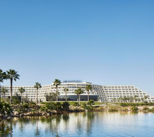 un grand hôtel avec des palmiers en face d'une étendue d'eau dans l'établissement JW Marriott Hotel Cairo, au Caire