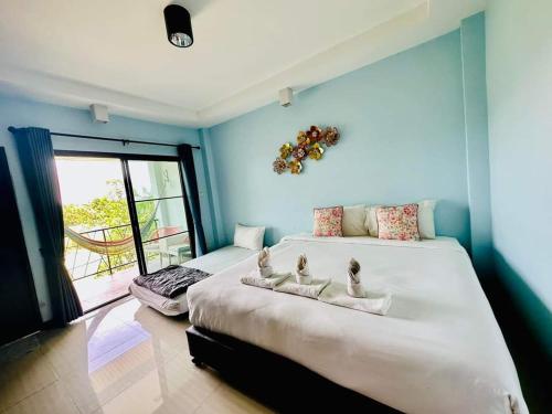 1 dormitorio con 2 camas, paredes azules y ventana en Na Na Doo Homestay, en Chiang Rai