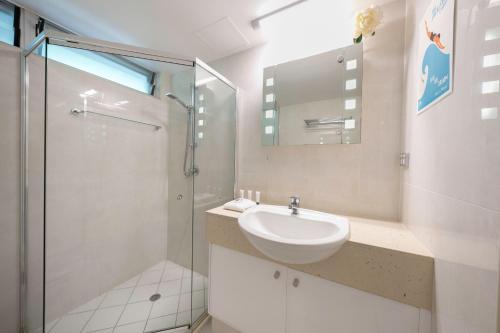 a white bathroom with a sink and a shower at Poinciana Lodge - 2 bedroom - on Hamilton Island by HIHA in Hamilton Island