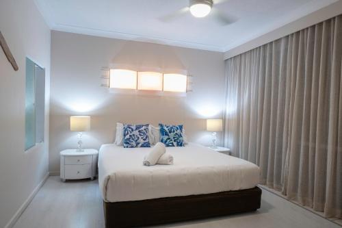 a bedroom with a large bed with blue and white pillows at Poinciana Lodge - 2 bedroom - on Hamilton Island by HIHA in Hamilton Island