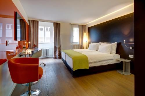 um quarto de hotel com uma cama e uma cadeira em Design Hotel f6 em Genebra