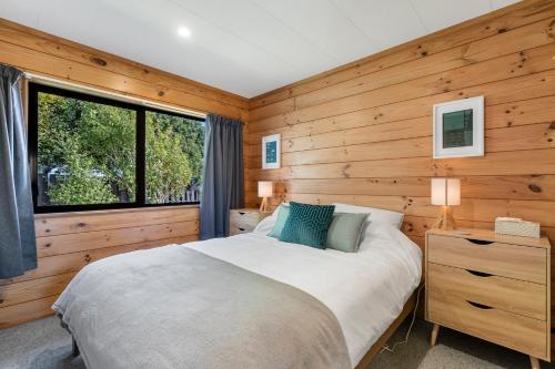 1 dormitorio con cama y ventana grande en Sunset Cottage - Waikanae Beach Holiday Home, en Waikanae