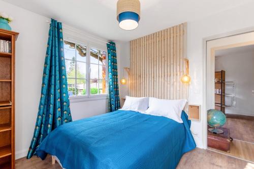 um quarto com uma cama azul e uma janela em Gîte le 11 em Le Merlerault