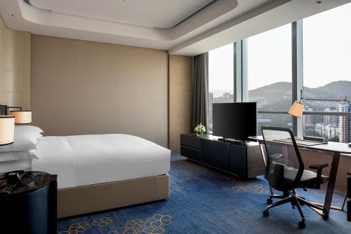 a hotel room with a bed and a desk with a computer at Hilton Jinan South Hotel & Residences in Jinan