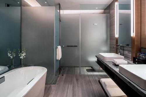 a bathroom with a tub and two sinks and a shower at Hilton Jinan South Hotel & Residences in Jinan