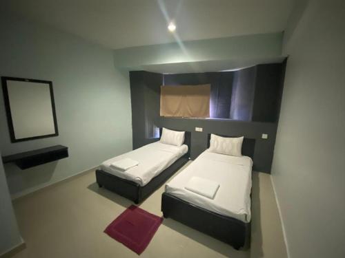 Cette petite chambre comprend 2 lits et un miroir. dans l'établissement OYO 90849 Hotel Hanarilla, à Kampong Batu Tiga