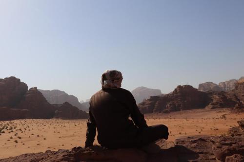 a person sitting on a rock in the desert at Enad desert camp in Wadi Rum