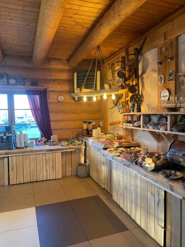 a kitchen with wooden walls and a counter with food at Hotel Pod Strzechą in Kielce