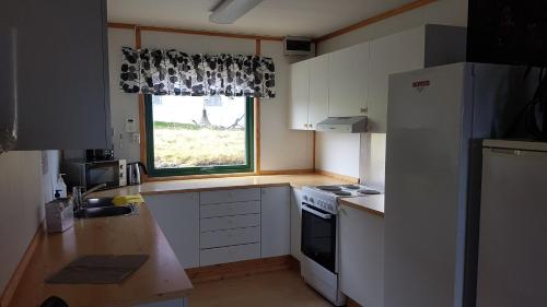 a kitchen with a white refrigerator and a window at Gamvik brakkebo as in Gamvik