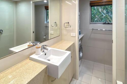 uma casa de banho branca com um lavatório e um espelho em The Cove Noosa - Apartment 6 em Noosa Heads