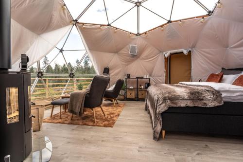 1 dormitorio en una tienda de campaña con 1 cama y sillas en Arctic Dome Gudbrandsdalen, en Sør-Fron