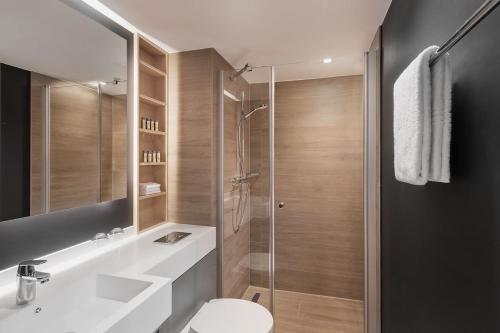 ein Bad mit einer Dusche, einem Waschbecken und einem WC in der Unterkunft Residence Inn by Marriott Hamburg Altona in Hamburg