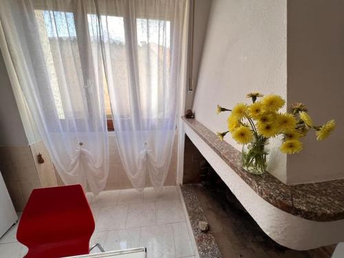 un baño con un jarrón de flores amarillas en un mostrador en Casa Viola, San Vito a 25 minuti da Costa Rey e Villasimius, en San Vito