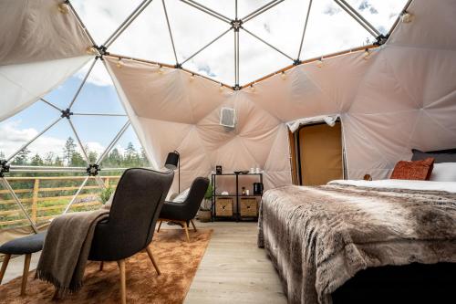 1 dormitorio en una tienda de campaña con 2 sillas y 1 cama en Arctic Dome Gudbrandsdalen en Sør-Fron