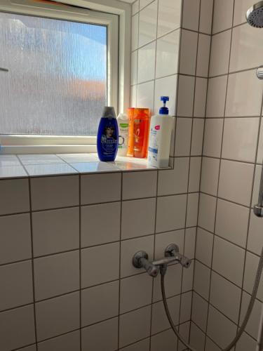 La salle de bains est pourvue d'une douche, de savon et de bouteilles sur une étagère. dans l'établissement Nice room near airport, à Copenhague