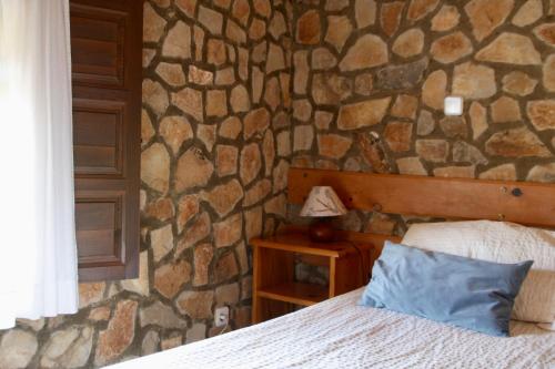 Un dormitorio con una pared de piedra y una cama en Casa Rural la Laguna, 