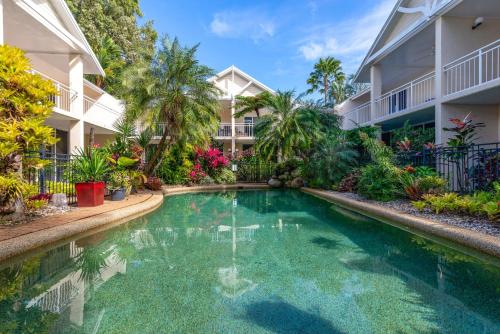 Una piscina frente a un edificio con árboles y plantas. en 3 Yaringa, en Port Douglas