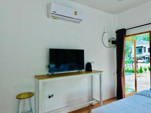 a bedroom with a tv on a dresser with a bed at Suanvadee Resort สวนวดี รีสอร์ท in Don Sak