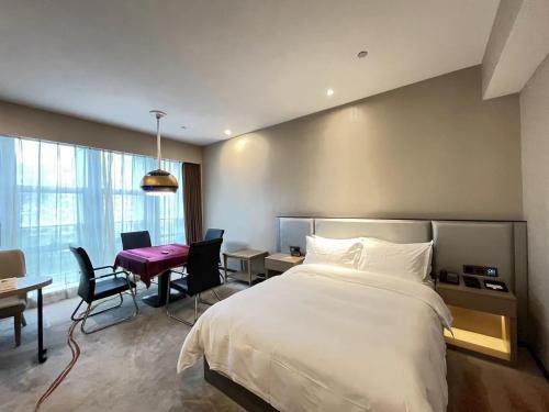 a hotel room with a bed and a desk and a table at Qingyuan Argyle Hotel in Qingyuan