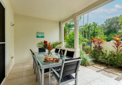 a dining room with a table and chairs on a patio at 7 Plantation House in Port Douglas