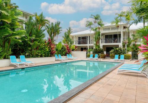 a swimming pool at a resort with blue chairs and palm trees at 7 Plantation House in Port Douglas