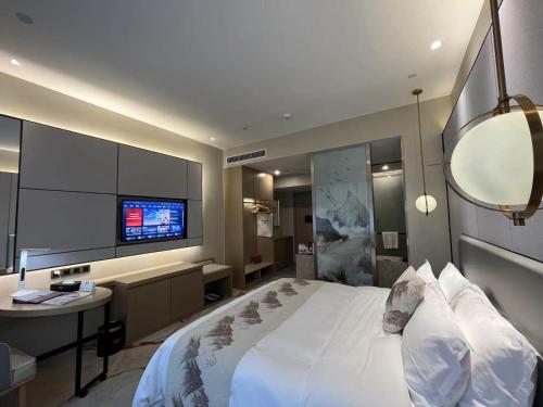 a bedroom with a large white bed and a tv at Qingyuan Argyle Hotel in Qingyuan