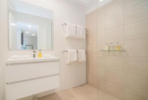 a white bathroom with a sink and a mirror at Beach Villa 5 in Port Douglas