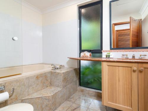 a bathroom with a tub and a sink at The Point Villa 10 in Port Douglas