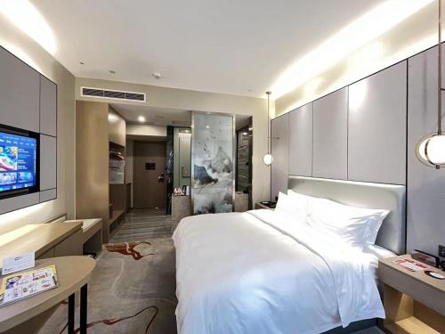 a bedroom with a large white bed and a tv at Qingyuan Argyle Hotel in Qingyuan