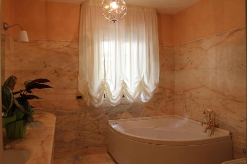 y baño con bañera y lámpara de araña. en B&B il Castello en Vico del Gargano