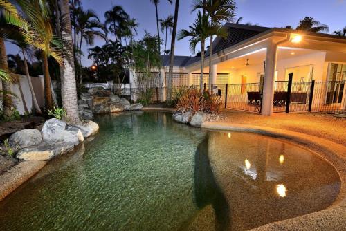 a pool of water in front of a house at Coral Drive Retreat in Port Douglas
