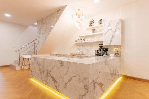 a kitchen with white marble countertops and a staircase at Homey Home at Hat Yai Perfect Place for Grouping in Ban Kohong