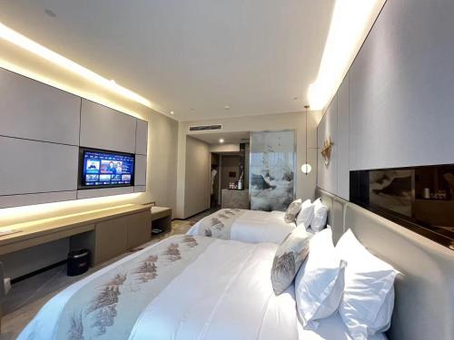 a hotel room with two beds and a flat screen tv at Qingyuan Argyle Hotel in Qingyuan