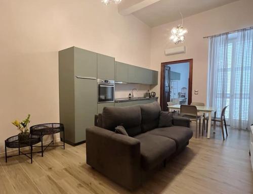 ein Wohnzimmer mit einem braunen Sofa und einer Küche in der Unterkunft La casa di Alice in Parma