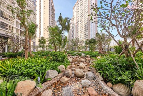 a garden with rocks and trees and tall buildings at Lalana Apartment in Ho Chi Minh City