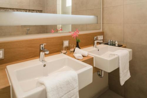 a white bathroom with two sinks and a mirror at Living Apartments Ludwigshafen in Ludwigshafen am Rhein
