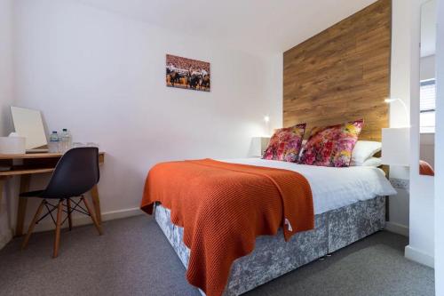 a bedroom with a bed with a wooden headboard and a desk at Beautiful Coach House in Gloucester