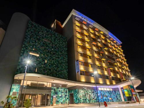 a large building with a lit up facade at night at Mercure Alger Palais Des Congres in Alger