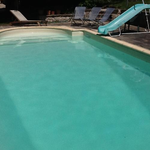 - une piscine avec un toboggan bleu dans l'établissement une fermette climatisée en pleine nature, à Moirax