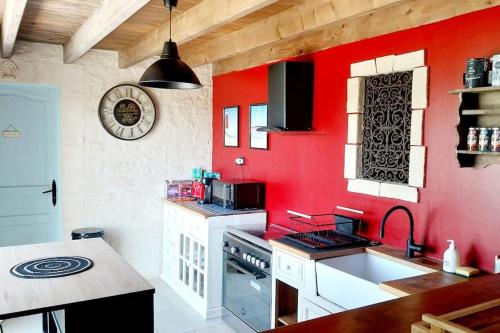 eine Küche mit einer roten Wand und einem Waschbecken in der Unterkunft Le Clos de Fanny - Belle longère charentaise in Burie