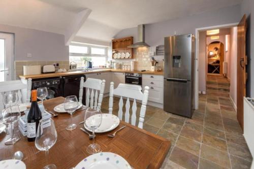 a kitchen with a wooden table with chairs and a refrigerator at Gorffwysfa Cottage, Garnfadryn, nr Abersoch in Dinas