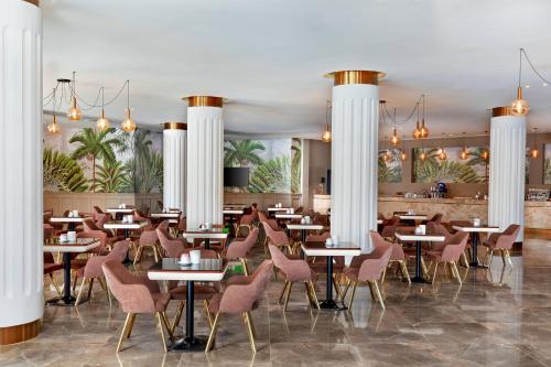a restaurant with white columns and tables and chairs at Neverland City Hurghada - Pickalbatros in Hurghada