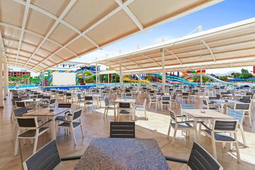 an empty restaurant with tables and chairs and rides at Neverland City Hurghada - Pickalbatros in Hurghada